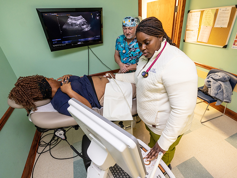 During her OB-GYN rotation with Dr. Ross Sherman (‘90), background, Mia McFadden performs an ultrasound for patient,  Vertoria Rivers. “She’s a star,” Sherman says of McFadden.